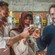 2 men and a woman hold up small glasses of beer in a brewery